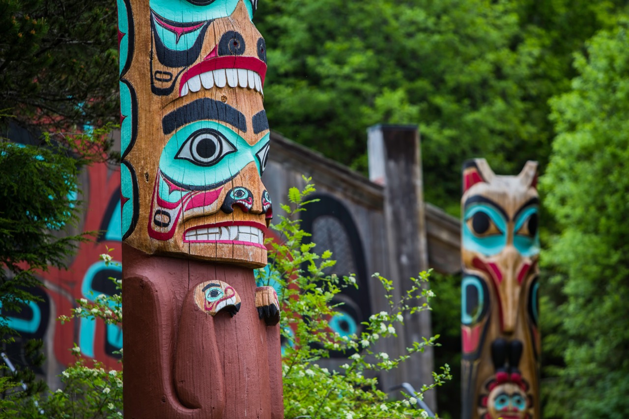 Detail of totem pole at Saxman Village tribal house near Ketchikan Alaska with Sun Raven in background; Shutterstock ID 438946603
