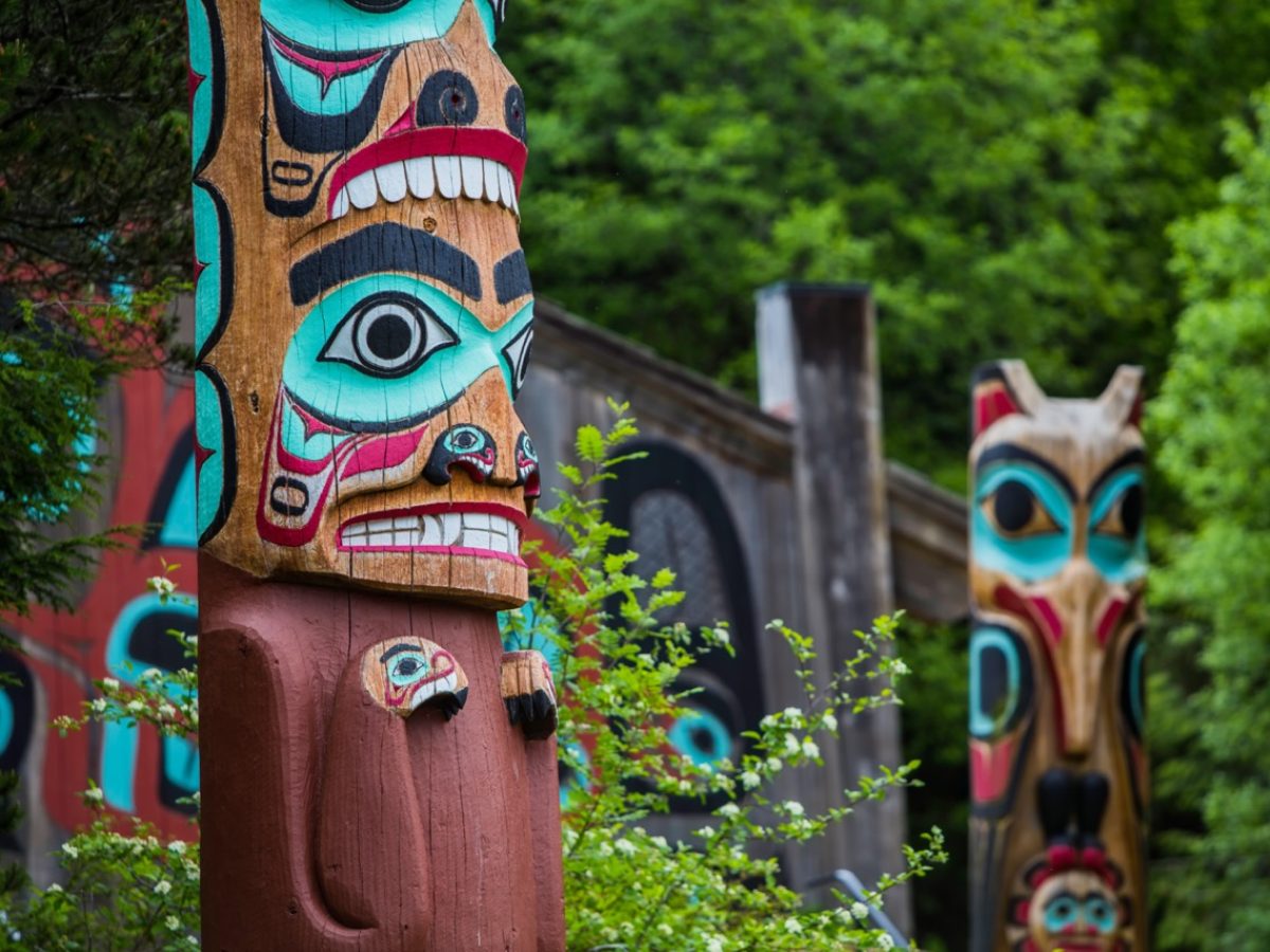 Detail of totem pole at Saxman Village tribal house near Ketchikan Alaska with Sun Raven in background; Shutterstock ID 438946603